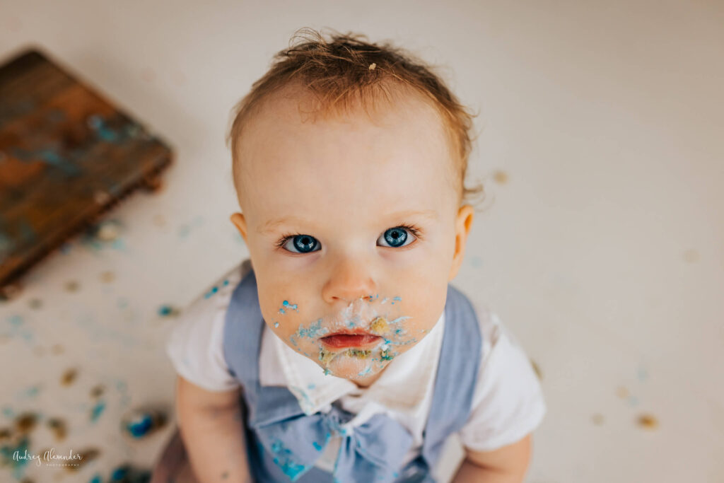 One year old enjoying his cake smash with cake all over face