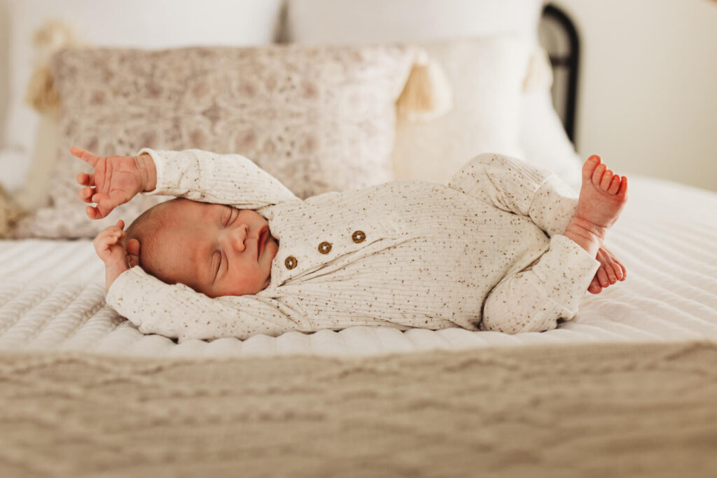Newborn baby stretching in bed in Smyrna