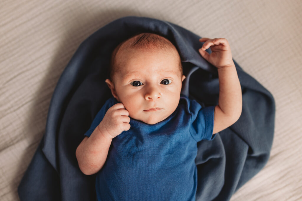 Newborn in swaddle in crib giving direct eye contact at Roswell home