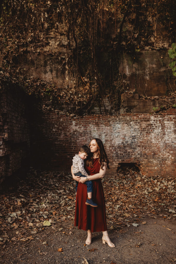 Mother holding tired child against a brick wall