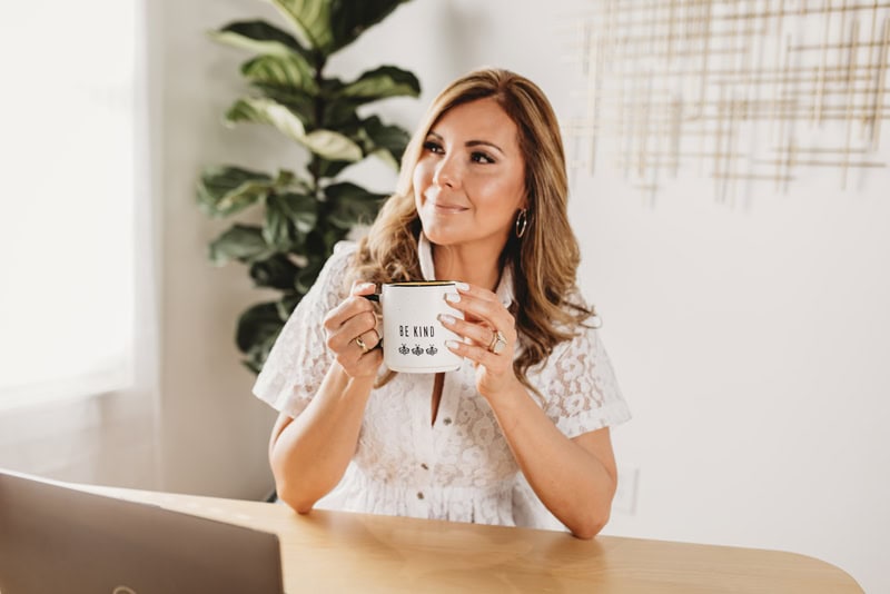 A woman enjoying a coffee mug at her home workspace.