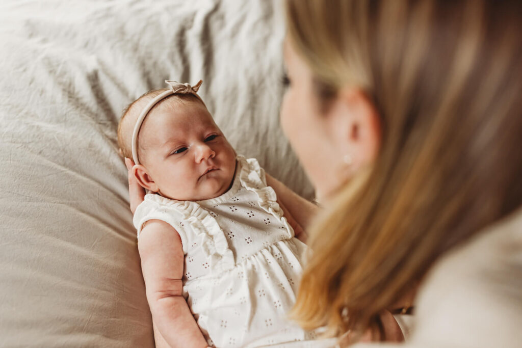 Mom holding a Newborn baby looking at her in a modern home in Milton, Georgia.