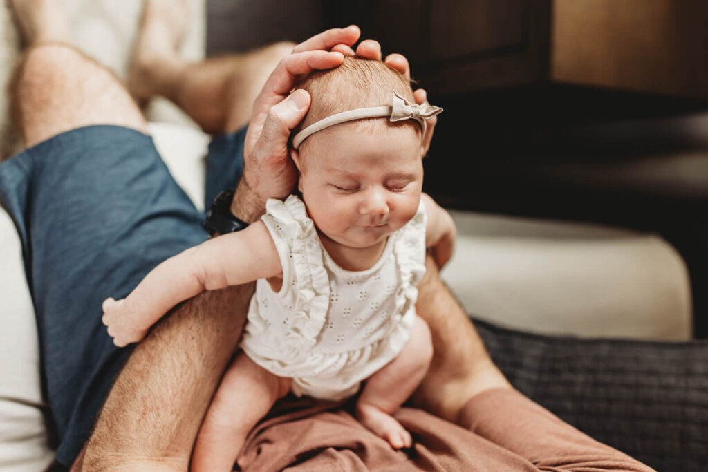 Dad holding a Newborn baby sleeping in a modern home in Milton, Georgia.