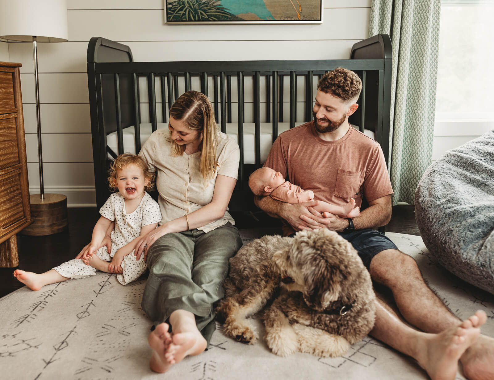 Family at a in-home newborn photography session cuddled in nursery in a modern Milton, GA home.