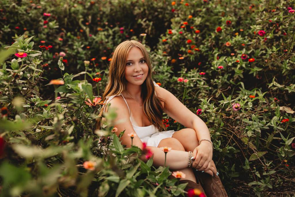 High school senior standing in colorful zinnias in Marietta
